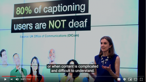 A woman in a blue dress standing in front of a slide saying: "80% of captioning users are NOT deaf" with text in front of her saying: "or when content is complicated or difficult to understand"